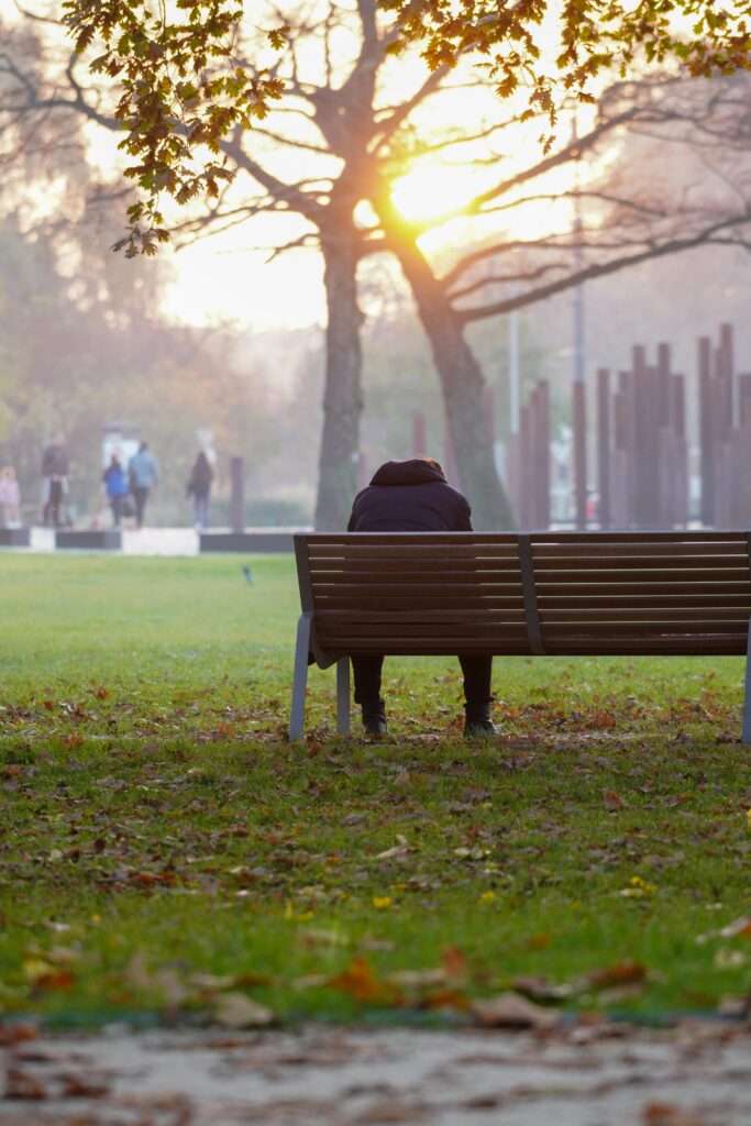 A solitary person sitting on a park bench at sunset, lost in deep thought and hear his inner voice(Echoes)
